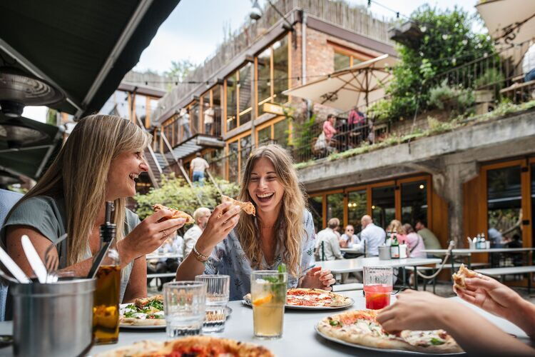 Los visitantes comen pizza en la terraza exterior del Standard, en PAKT.