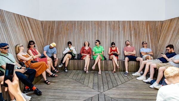 Visiteurs profitant du beau temps sur la terrasse du M HKA sur un banc en bois.