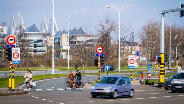 Een afbeelding van een druk kruispunt waar verkeersborden aanduiden dat er een lage emissiezone van kracht is. 