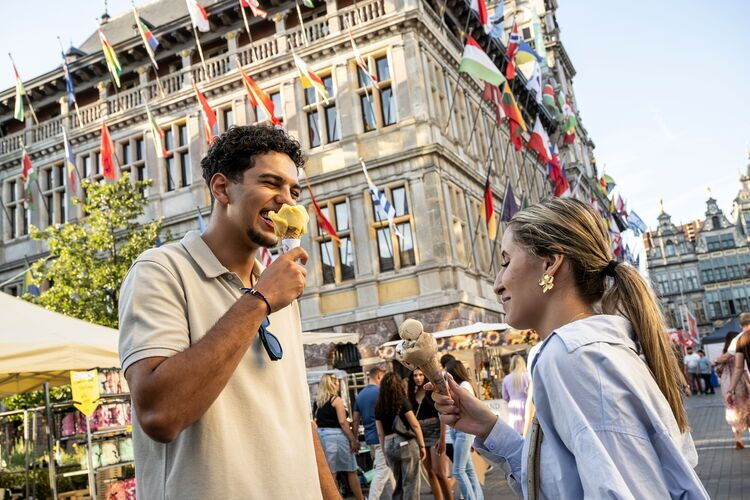 Un homme et une femme mangent une glace près de l'hôtel de ville, sur la Grand-Place, pendant le marché Rubens