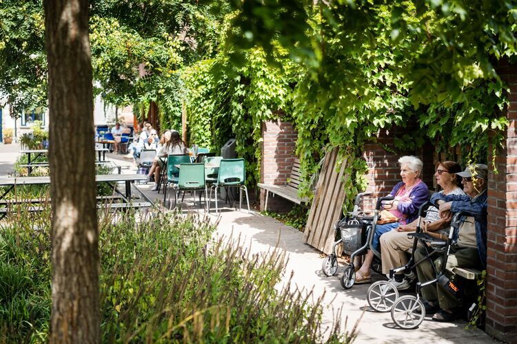 3 senioren genieten op een bankje van de sfeer in het Munthof