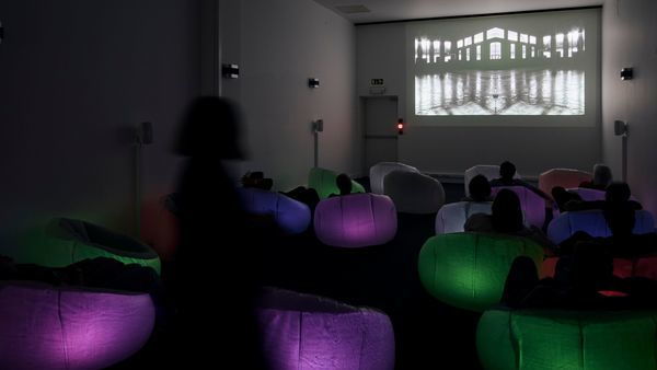 M HKA, les visiteurs regardent un film dans une salle obscure du musée.