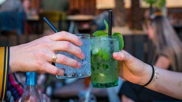 Two people clinking with cocktails in hand