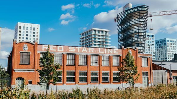 A red, brick building on which Red Star Line stands. A modern tower rises above it. In the background some skyscrapers.