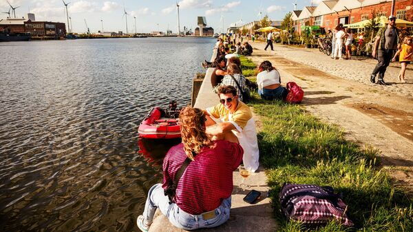Menschen genießen am Wasser ein Getränk in der Bar Paniek.