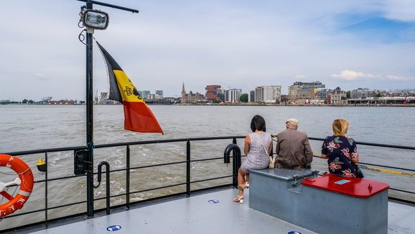 People sit on the deck of a ferry and look at the view of Antwerp's right bank, which includes the MAS | Museum aan de Stroom in the het Eilandje district.