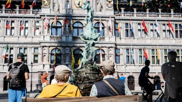 Twee heren op een bankje op de Grote Markt staren naar Brabo en het stadhuis.