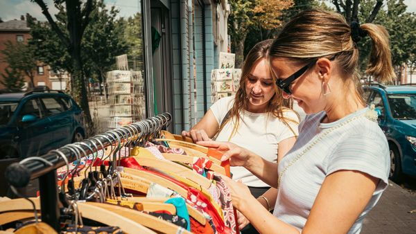 2 filles regardent un porte-vêtements dans un magasin d'antiquités de la rue du Monastère