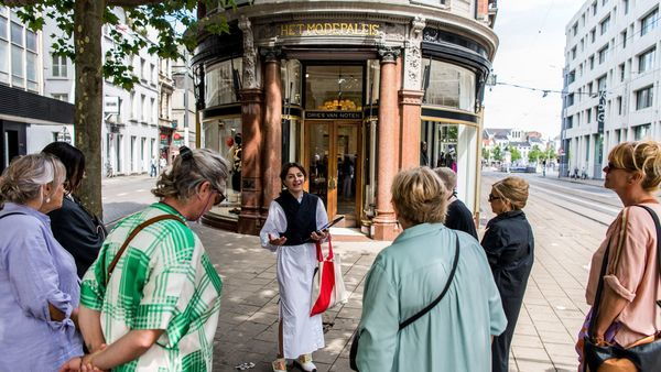 Un groupe de personnes se tient devant le Fashion Palace, le magasin phare de Dries Van Noten.