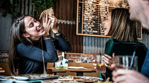 Woman eating pizza at Otomat