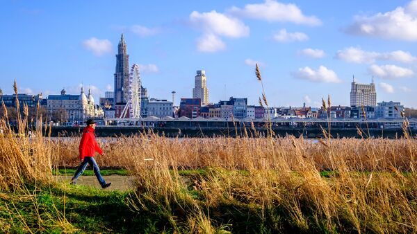  Man walks on the Left Bank with a view of the Antwerp skyline.