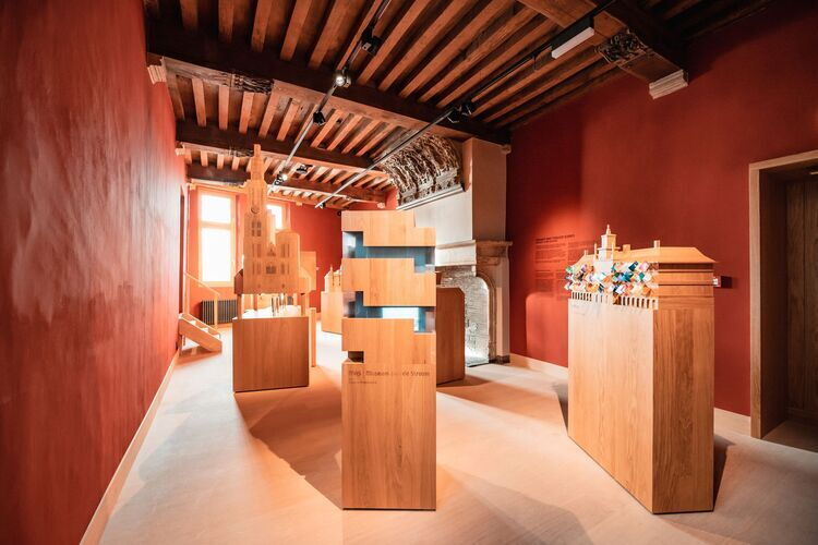 Interior of Het Steen museum in Antwerp, featuring wooden models and interactive exhibition pieces in a historic space with red walls and exposed wooden ceiling beams.