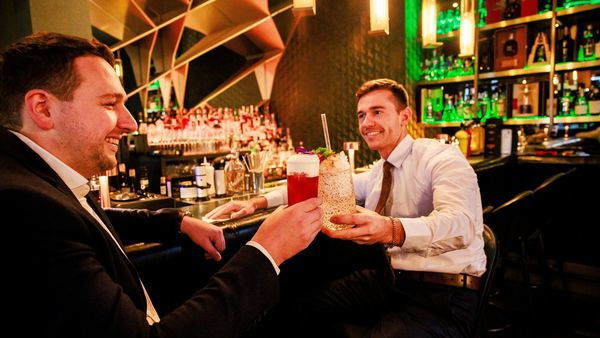 Deux hommes tenant des cocktails.