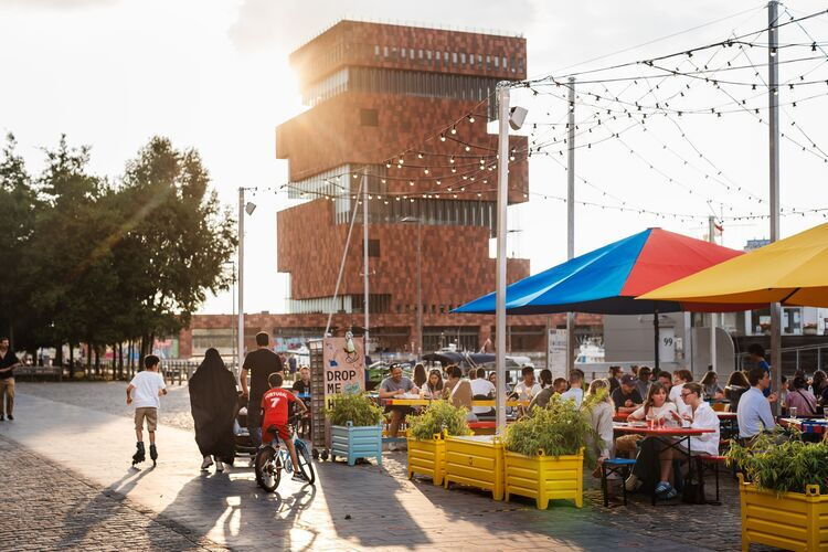 People enjoy delicious food and drinks on Wolf's terrace with a beautiful view of the MAS.