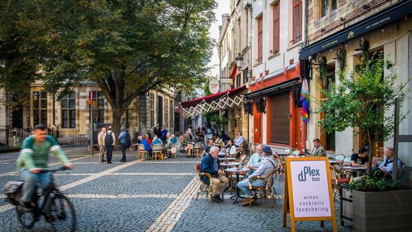 Mensen zitten op terras aan Hendrik Conscienceplein