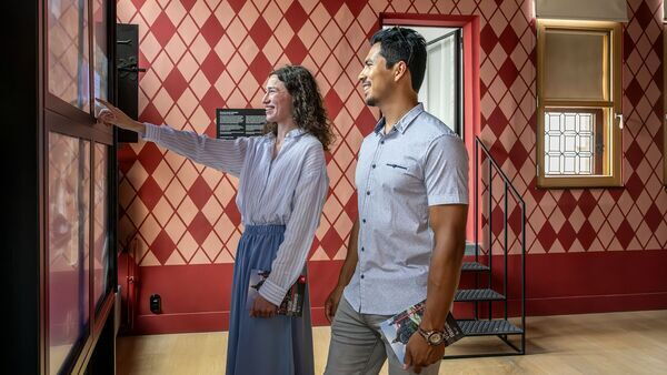 Vrouw en man raken een digitaal scherm aan in een mooie historische kamer in the Antwerp Story