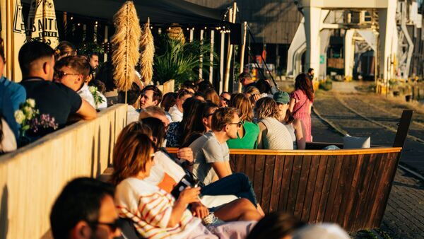 People enjoy sun, drinks and good company on the terrace of Gazon Antwerp