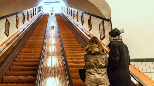 La gente toma la escalera mecánica de madera en el túnel peatonal.