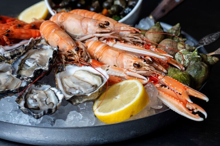 Fruits de mer sur lit de glace, avec des huîtres, des grosses crevettes et un quartier de citron, servis en plateau de fruits de mer.