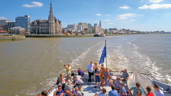 Groupe de personnes sur un bateau avec la ligne d'horizon d'Anvers en arrière-plan